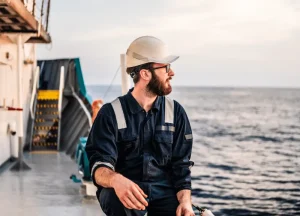 Commercial fisherman in safety gear working on wet deck.