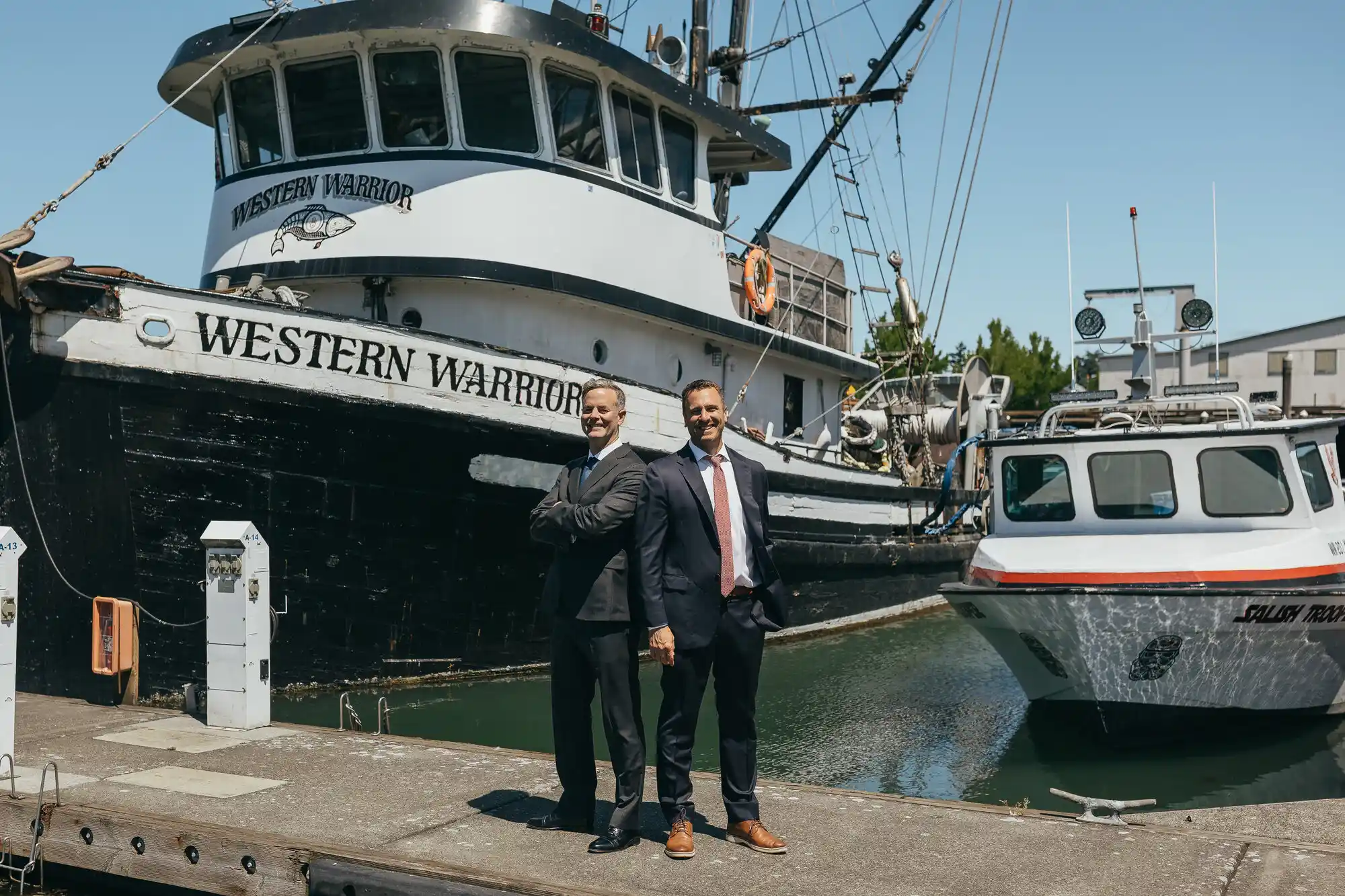 Two BoatLaw attorneys in business suits walking posing in front of a water vessel